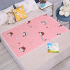 Pink cartoon patterned waterproof bed protector pad with animal designs on a light colored surface