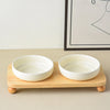 Two white ceramic bowls with a wooden stand for pets