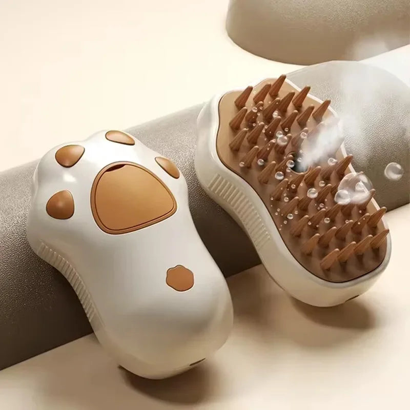 A white electric pet grooming brush with a brown silicone comb and steam feature resting on a gray surface.
