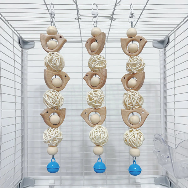 Three decorative wooden parrot swing toys hanging in a clear wire cage