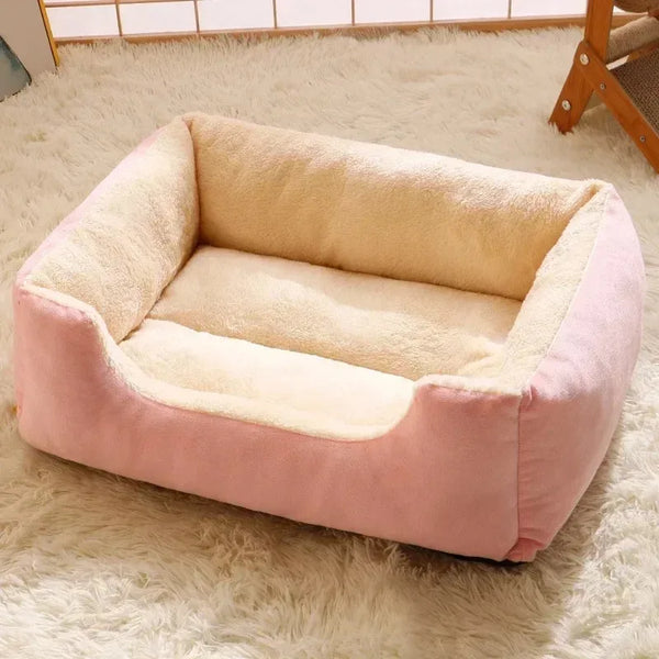 A pink plush cat bed with a beige cushion resting on a fluffy white rug.