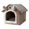 A gray removable dog house pet bed with a pitched roof and entrance for indoor use.