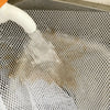 A white liquid is being poured into a mesh safety net used for balcony or stairs.