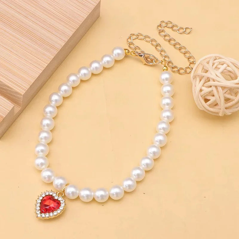 Un délicat collier de perles avec un pendentif de pierre rouge et une chaîne en or.