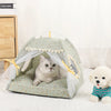A gray cat is relaxing inside a light green pet tent bed decorated with sheer white fabric and yellow accents.