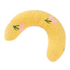 Un coussin d'animal jaune et duveteux en forme de corps courbé avec des accents floraux roses.