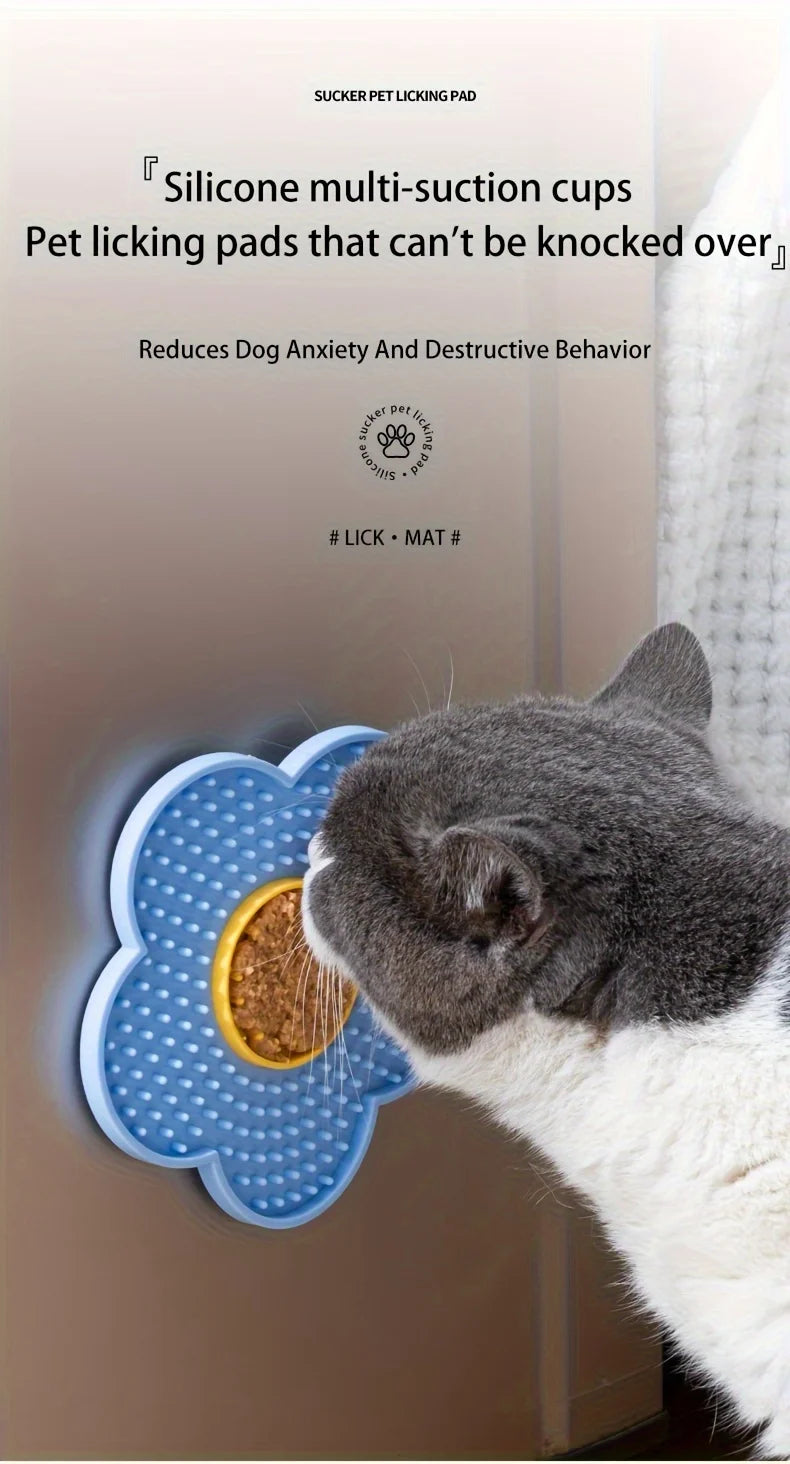 A gray and white cat is licking a blue silicone multi-suction pet licking pad.