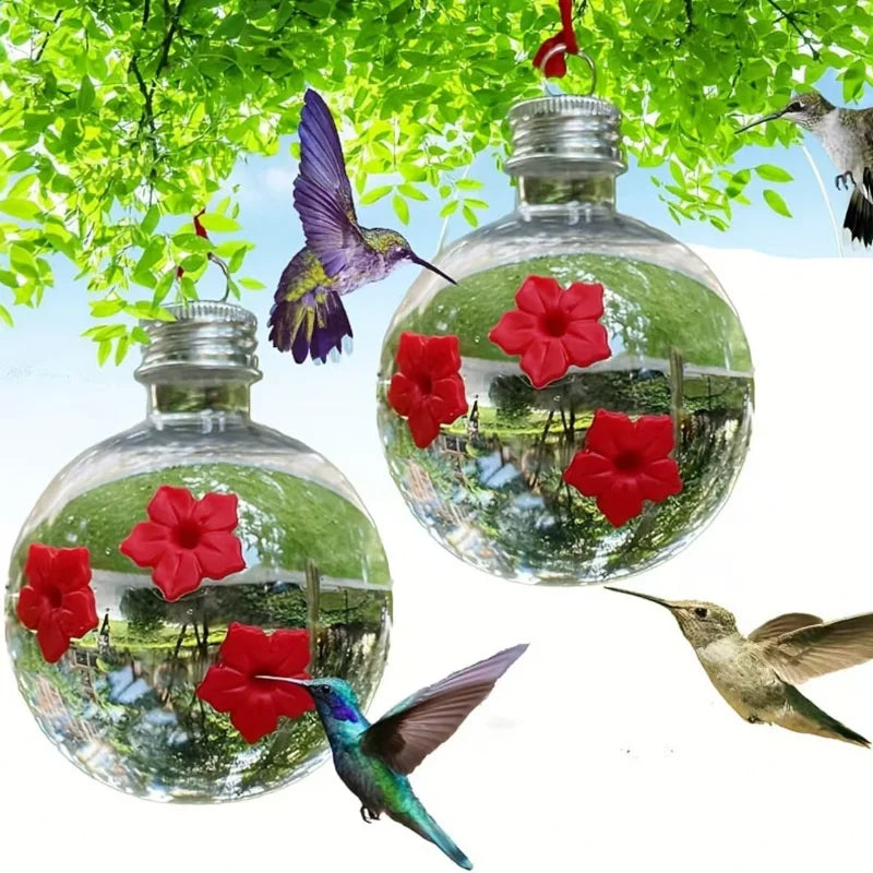 Un distributeur d'eau sphérique en verre rempli d'eau, avec des fleurs rouges et des feuilles vertes, suspendu dans un cadre 