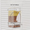 Automatic parrot feeder with husk separation visible inside a white grid panel.