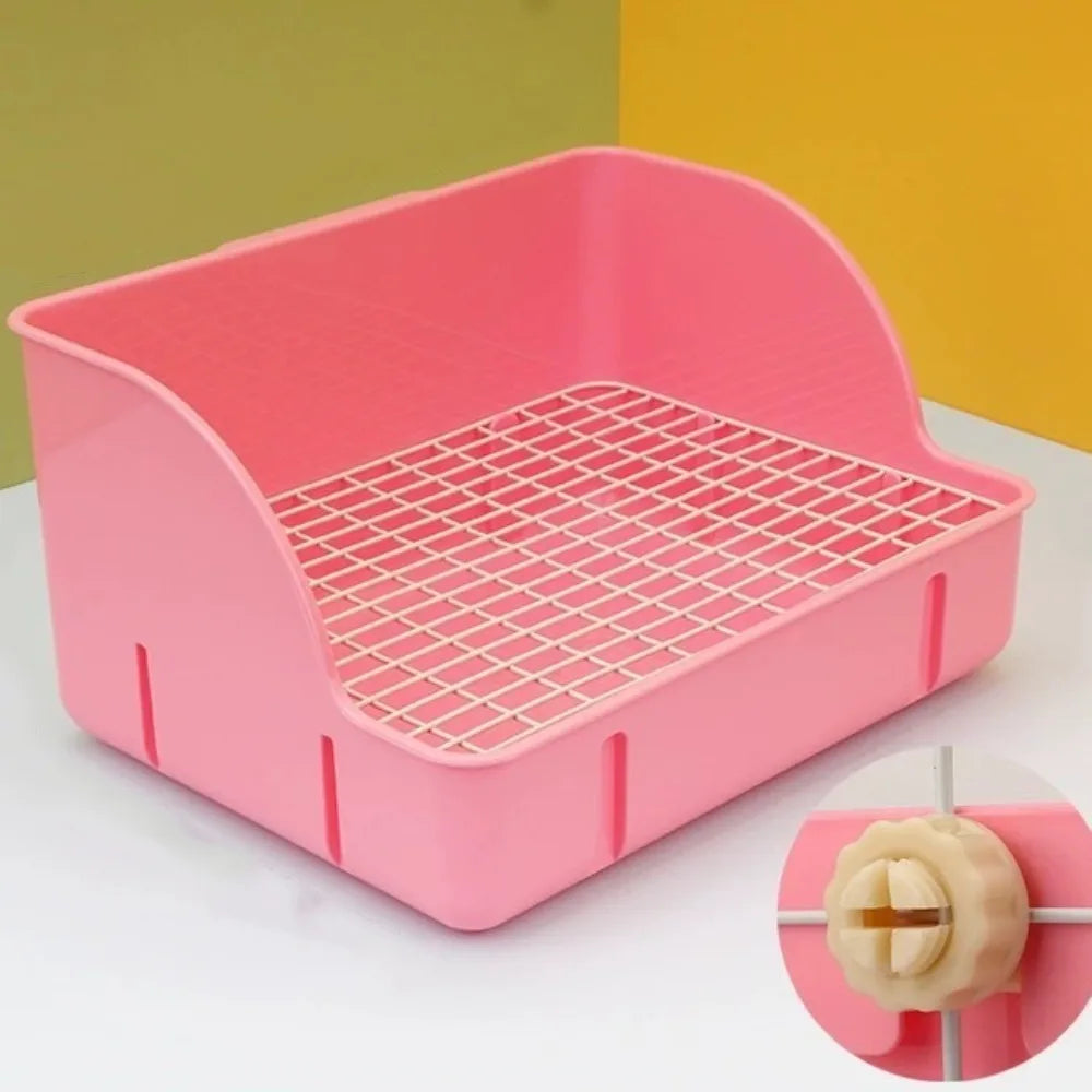Una caja de arena rejilla rosa desmontable para pequeños mamíferos, mostrada sobre una superficie blanca.
