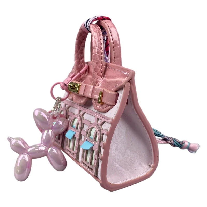 A handcrafted mini house-shaped bag in pink with a puppy keychain charm.