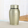 A matte gold stainless steel pet memorial storage box with a black lid sitting on a light surface.