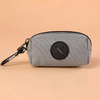 Pochette grise à fermeture éclair avec un motif croix circulaire noire et un clip métallique.