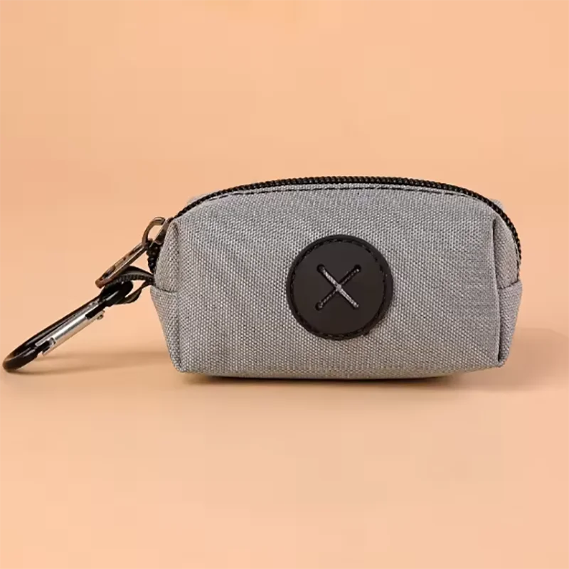 Pochette grise à fermeture éclair avec un motif croix circulaire noire et un clip métallique.