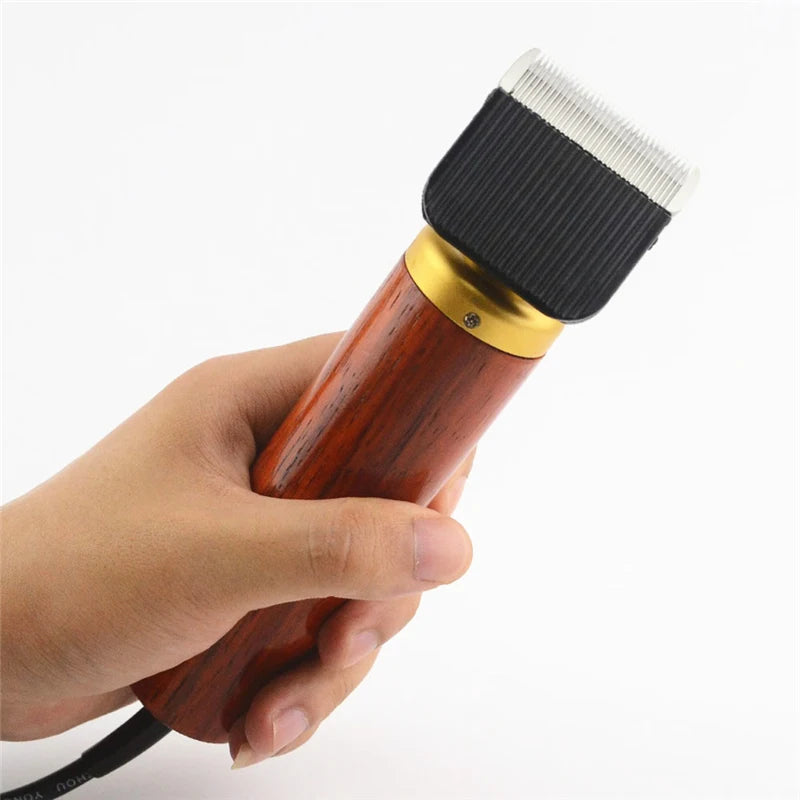 A hand holds a professional corded pet clipper with a wooden handle and a black brush head.