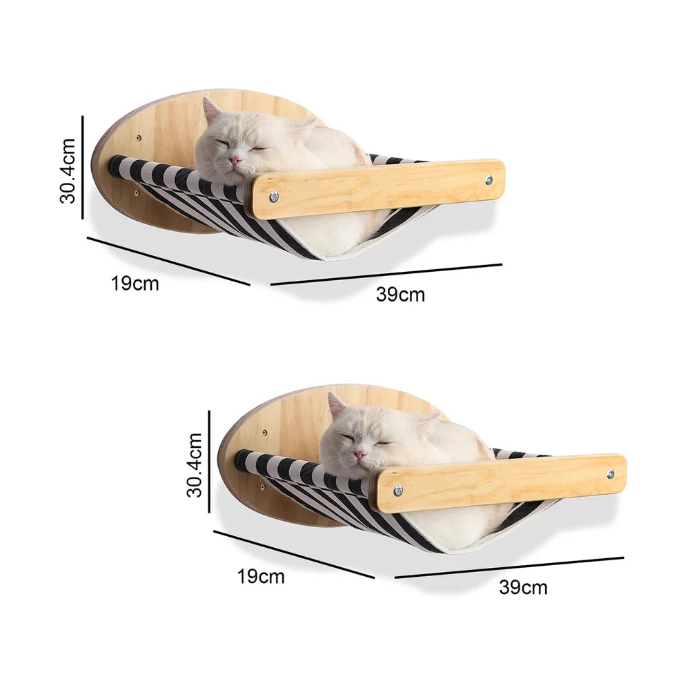 A fluffy white cat is relaxing in a wooden hammock-style shelf mounted on a circular wooden base.