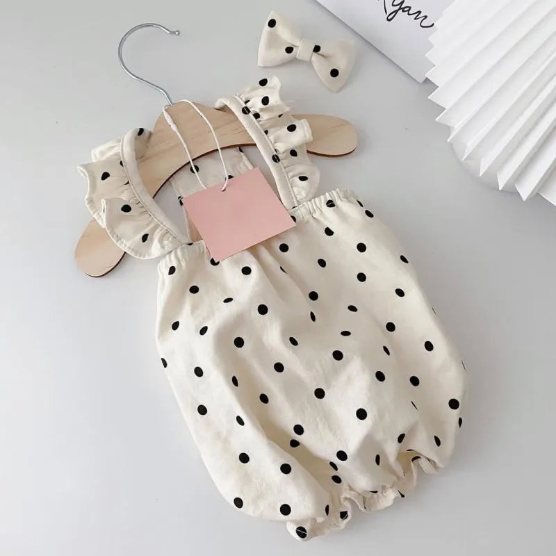 A cream-colored pet dress for a small dog featuring black polka dots and ruffled details.