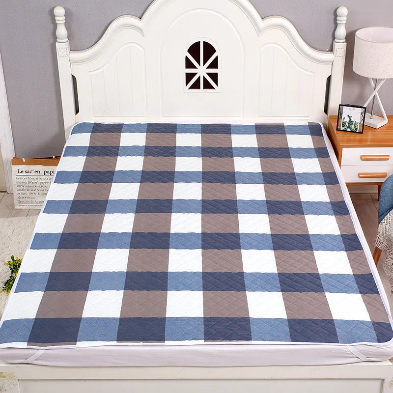 A plaid bed protector pad featuring blue, gray, and white checks displayed on a white wooden headboard.
