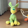 A yellow and green squeaky donkey plush toy with large ears sitting on a wooden floor.