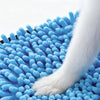 Une patte blanche et duveteuse repose sur une serviette de bain pour animaux bleue et texturée.