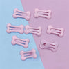 Several pink bone-shaped hair clips are displayed on a light blue and pink background.