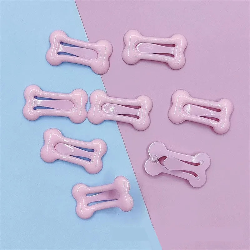 Several pink bone-shaped hair clips are displayed on a light blue and pink background.