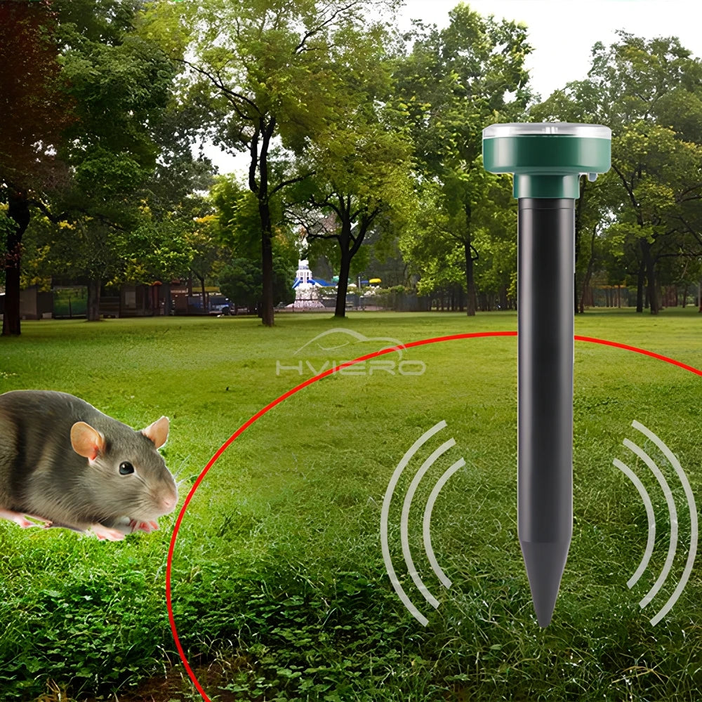 A black ultrasonic pest repeller device with a green top is shown in a grassy outdoor setting with a rodent nearby.