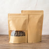 Two kraft paper zipper bags filled with dried herbs or tea leaves are displayed on a wooden surface.