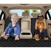 A golden retriever dog is sitting in a car seat cover with an armrest, next to a young child.