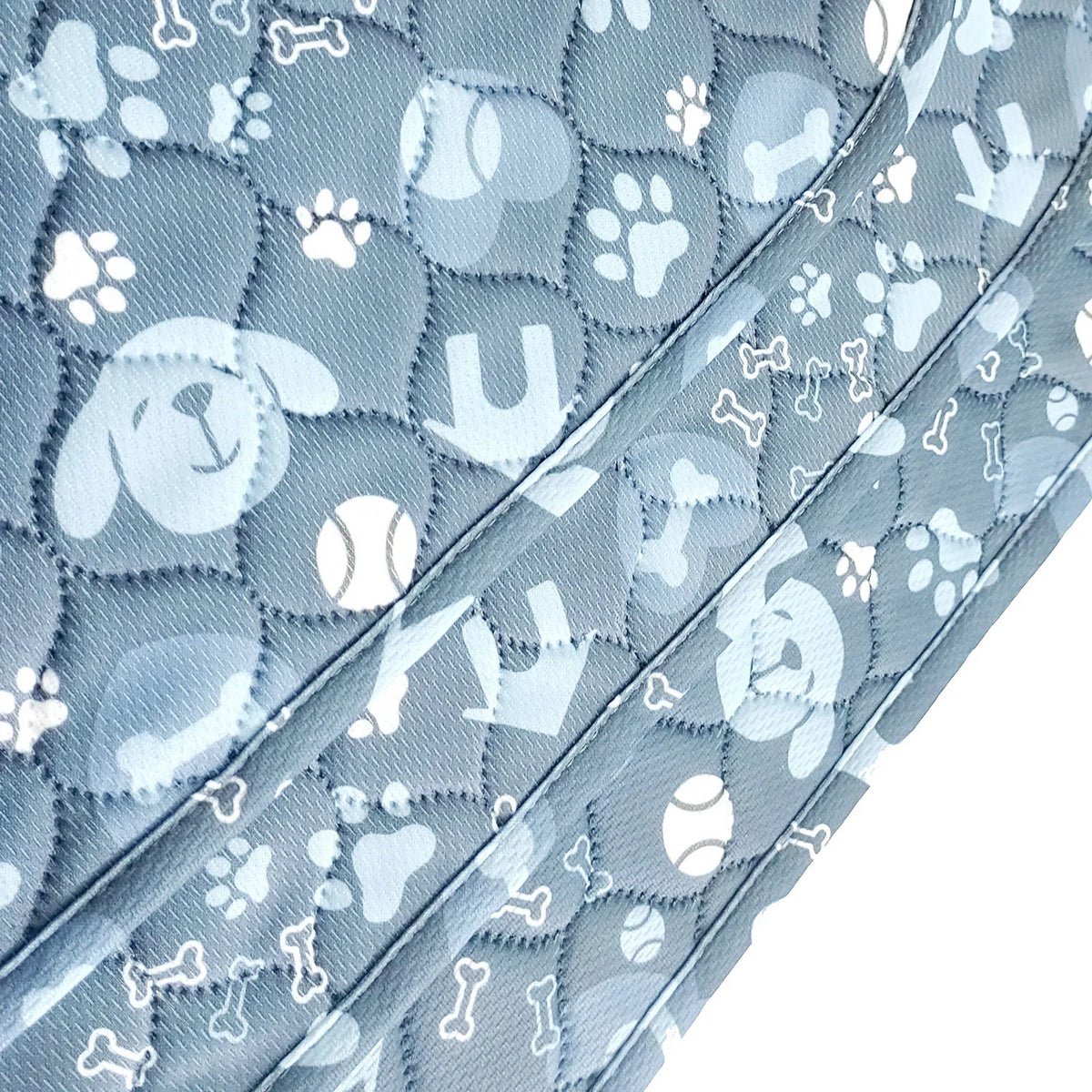 A close-up of a light blue reusable dog pee pad featuring a repeating paw print pattern.