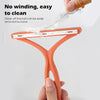 An orange silicone tool used to clean pet hair off a ball, demonstrating its easy removal feature.