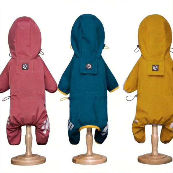 Three waterproof dog raincoats in shades of pink, teal, and yellow displayed on wooden stands.
