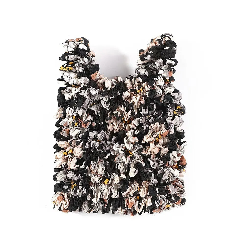 A close-up of a reusable foldable bubble shopping bag made from black and beige crinkled material.