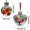 Un distributeur en forme de cœur en verre clair avec des fleurs rouges, suspendu par un capuchon et une ficelle en argent.