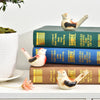 Keramisches Wasservogel-Signalhorn in Weiß und Schwarz auf einem Stapel grüner Bücher.