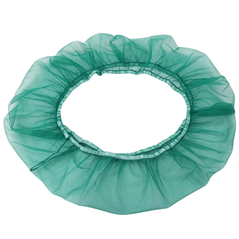 A circular skirt made of sheer teal nylon mesh used as a debris guard for a bird cage seed catcher.