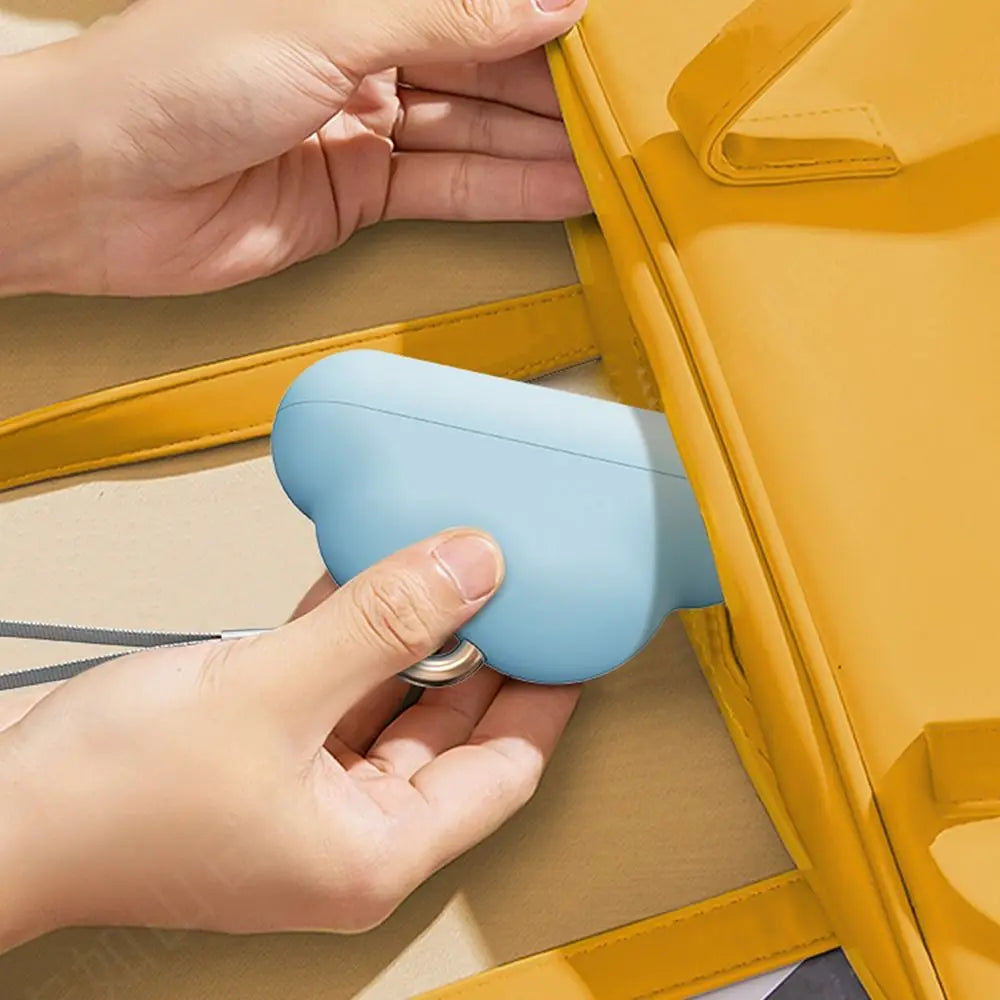 A hand is holding a light blue, cloud-shaped lint roller refill against a yellow storage box.