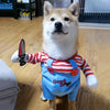 A light-colored dog wearing a red and white striped shirt and a blue overalls costume with the words Good Dogs on it.