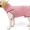 A light-colored dog is wearing a pink fleece sweater with a high collar.