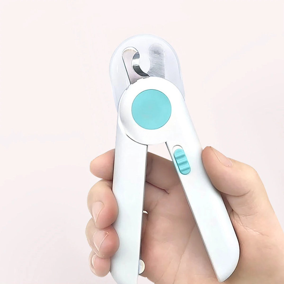 A hand holds a white pet nail clipper with a light blue accent, showing the professional grooming tool.