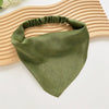 Diadema o pañuelo de seda verde oliva sobre una superficie de madera clara.