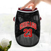 A black dog sports jersey with red lettering and the number 23 is being held by a hand.
