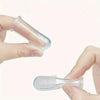 A hand holds a clear silicone pet toothbrush, showing the brush head and handle.