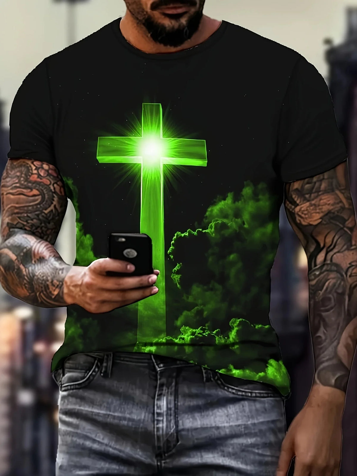 A man wearing a black t-shirt with a glowing green cross design, holding a smartphone.