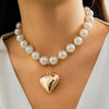 A close-up of a pearl choker necklace with a heart pendant worn around the neck.