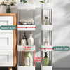 A white mobile storage rack with three tiers holding various bottles and plants on a wooden cabinet.