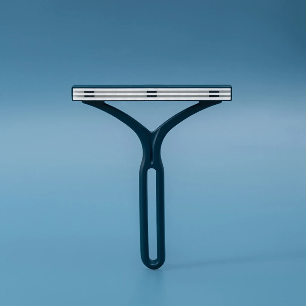 A teal manual lint remover brush with a silver bar is shown against a solid blue background.