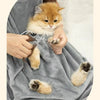 Un pequeño gatito atigrado naranja es sostenido por una persona dentro de un delantal transportador para mascotas gris exteri