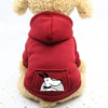 A red cozy fleece dog sweatshirt with a hood and patch pocket worn by a fluffy dog.