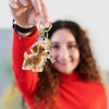 A woman holds up a transparent pet hair memorial keychain featuring a small dog figurine.